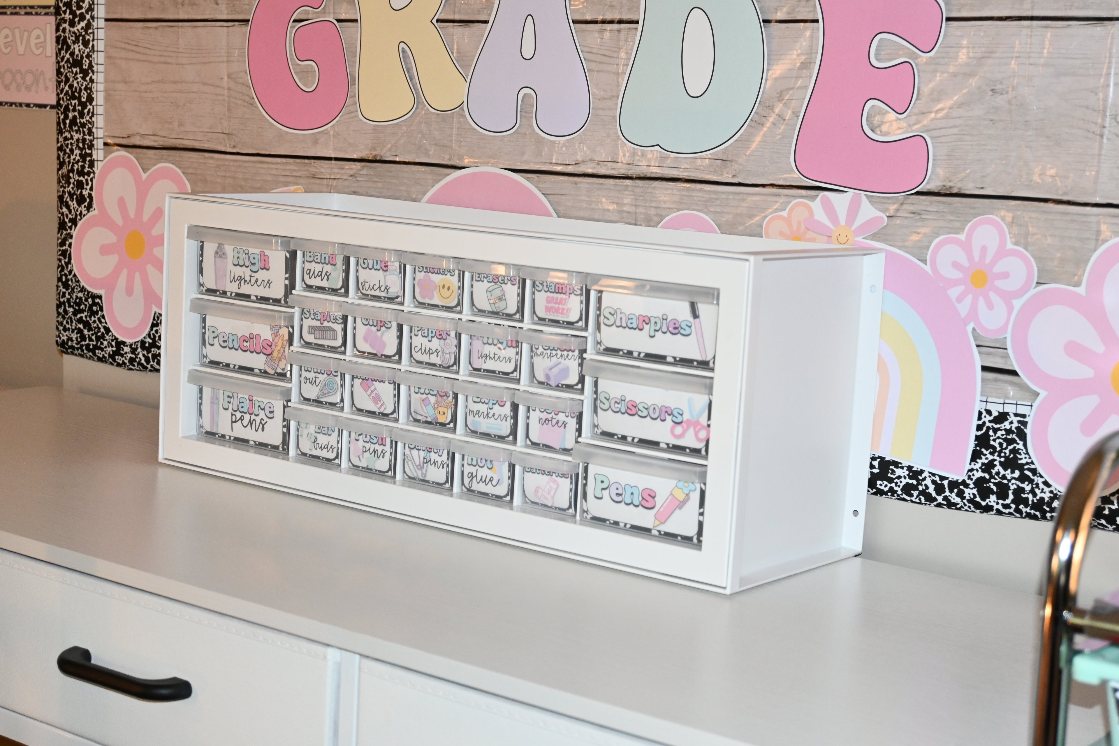 White organizer with labeled compartments on a desk with decorative elements in the background